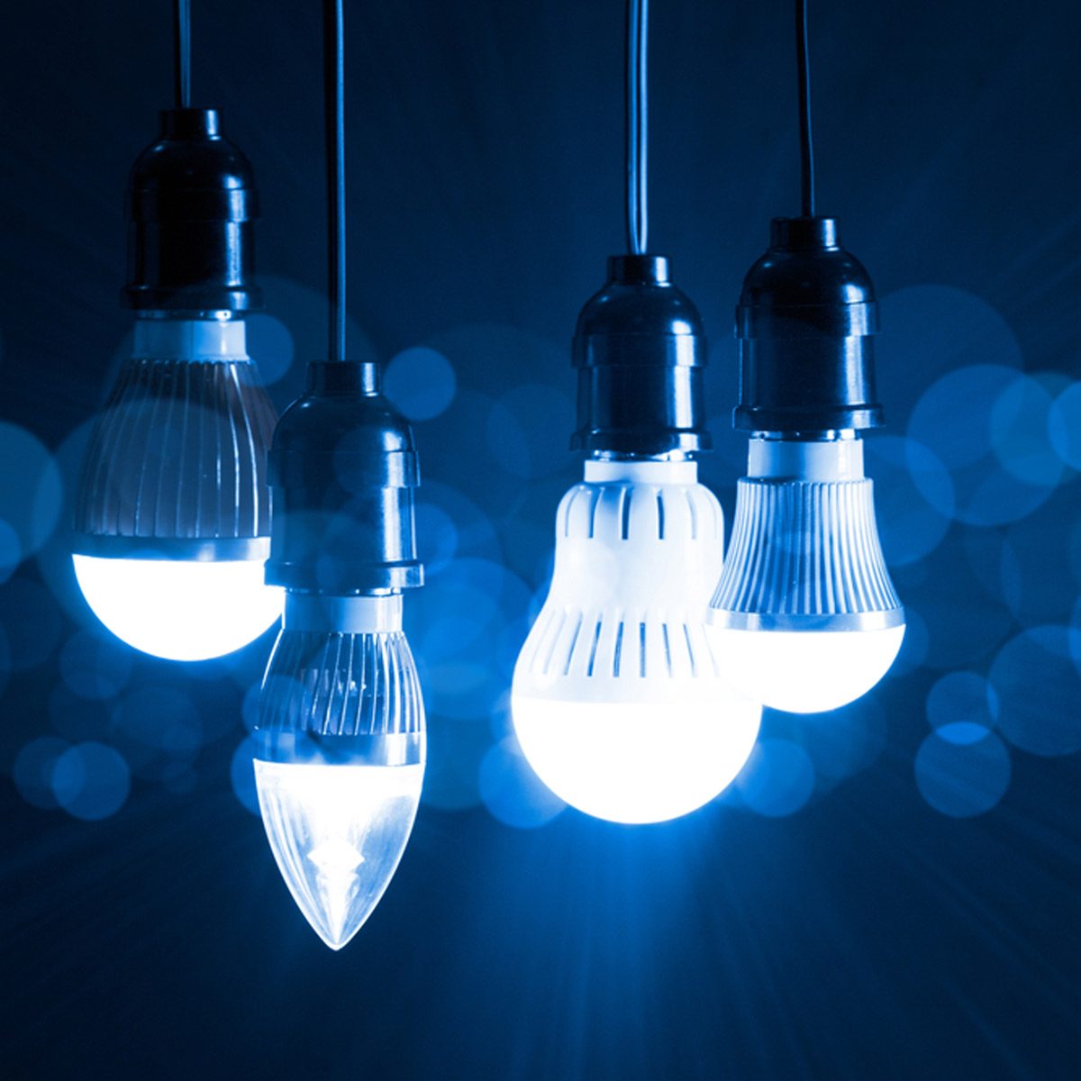 Five hanging light bulbs illuminate with a soft blue glow against a dark background, creating a tranquil and atmospheric setting.