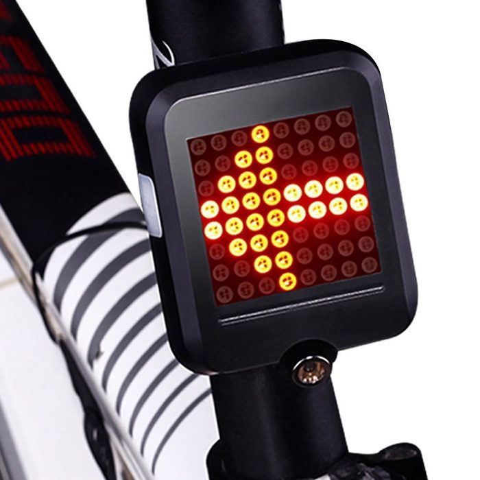 A rectangular bike signal light displays an illuminated arrow, indicating direction. It's mounted on a bike’s frame, surrounded by sleek black and white patterns.