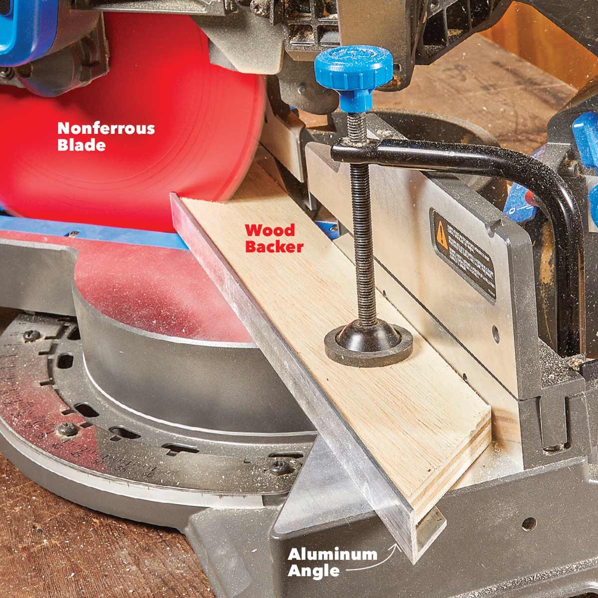 A miter saw equipped with a nonferrous blade cuts through a piece of wood, supported by a backer and an aluminum angle, on a workshop table.