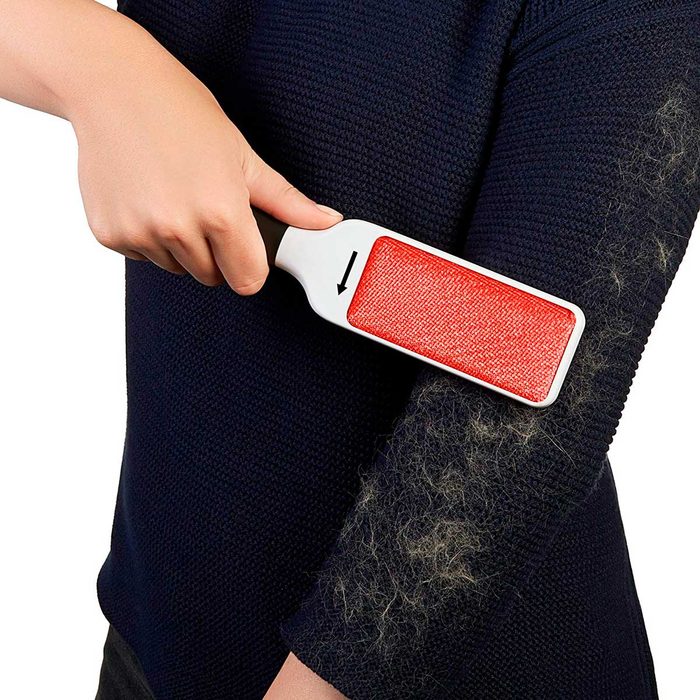 A person uses a lint roller to remove pet hair from a dark sweater, enhancing the garment's cleanliness in a personal care context.