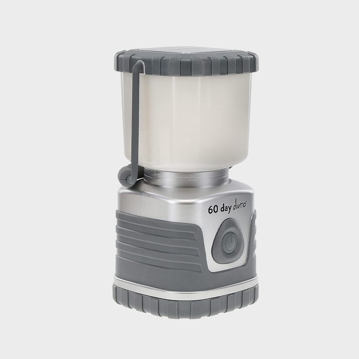 A gray and silver lantern illuminates the surroundings, designed for extended use with a button for easy operation and a sturdy base for stability.