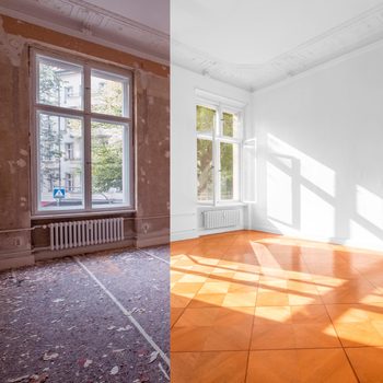 A window separates two rooms: one in renovation with bare walls and debris, and the other is bright with polished wooden flooring and sunlight streaming in.