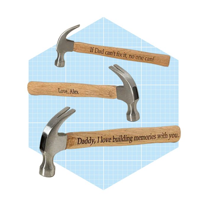 Three hammers with engraved messages rest against a light blue grid background, conveying affectionate sentiments from children to their fathers.