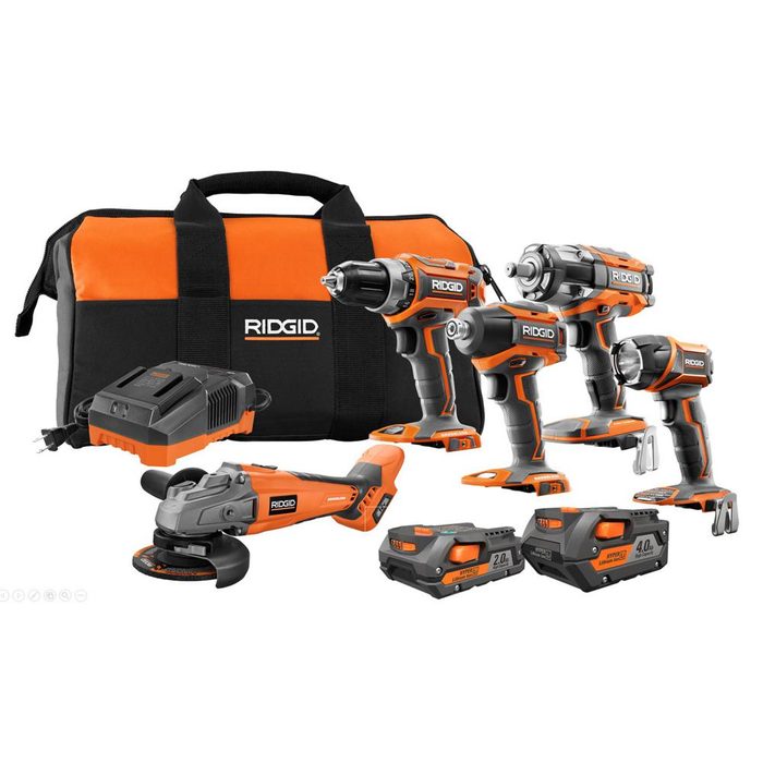 A set of orange and black RIDGID power tools, including drills and a grinder, is displayed alongside batteries and a charger in a carrying case.