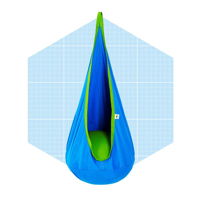 A blue and green hanging chair sways gently, suspended in a minimalist environment, with a grid-patterned background providing a stark contrast.