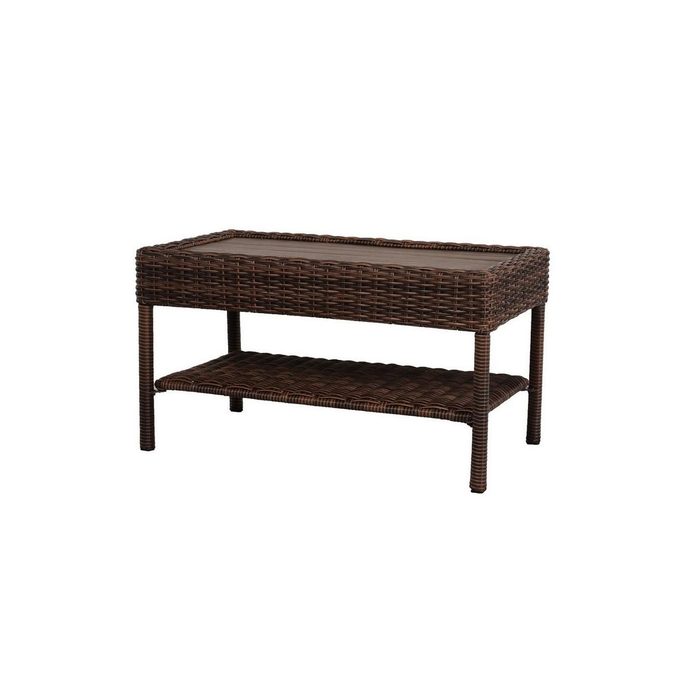 A rectangular coffee table with woven brown material, featuring a glass top and a lower shelf for storage, is positioned as a functional furniture piece.