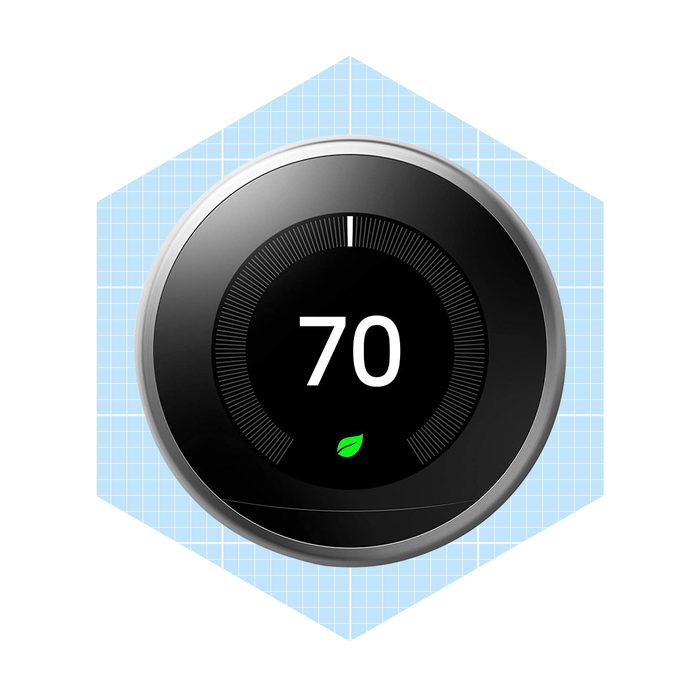 A round thermostat displays a temperature of 70, featuring a green leaf symbol, set against a light blue grid-patterned background.