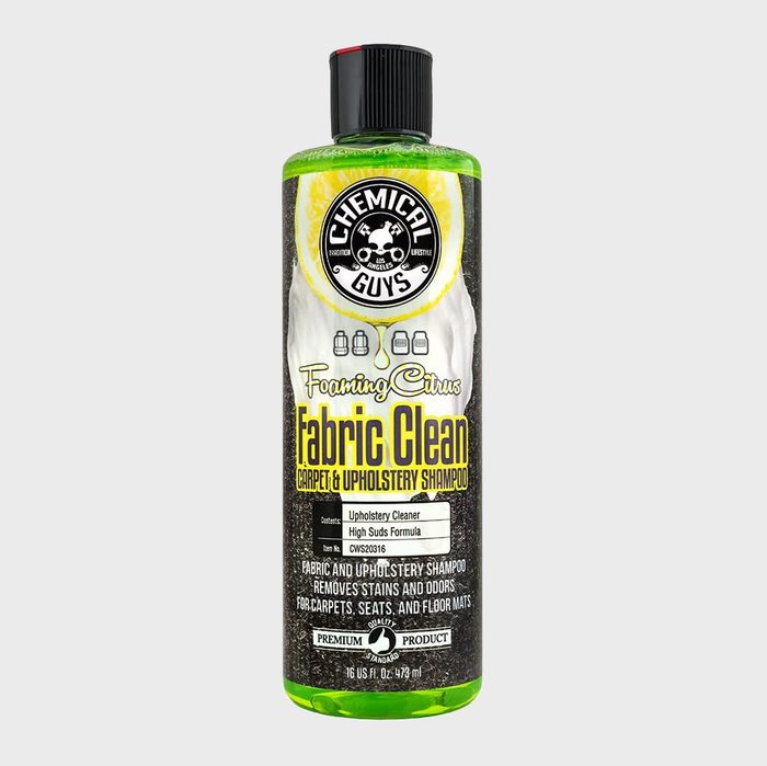 A bottle of foaming carpet and upholstery shampoo is displayed, labeled for cleaning fabrics with citrus scent, featuring a black and green design.