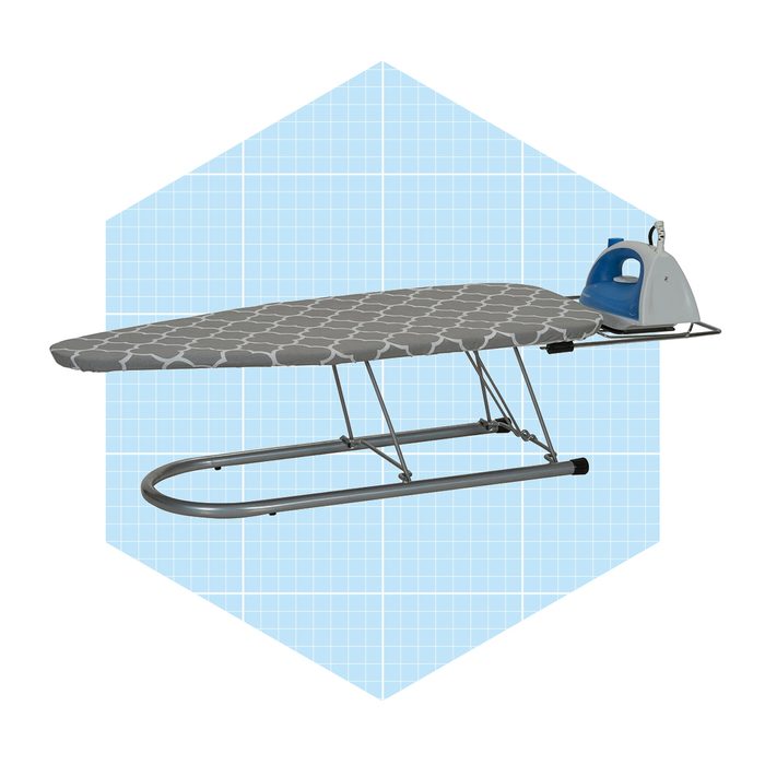 An ironing board with a patterned cover holds a blue iron, set against a light blue, grid-patterned background.