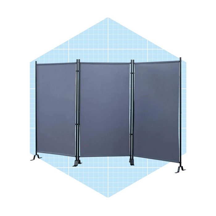 A three-panel room divider stands upright, blocking visibility. The backdrop features a light blue grid pattern, enhancing the divider's presence in a defined space.