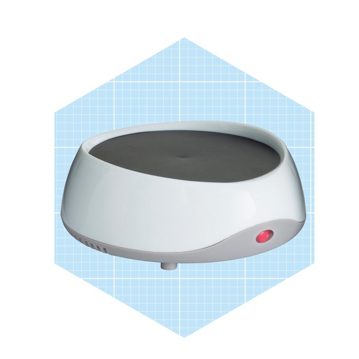 A sleek, white object with a black top rests in a light blue hexagonal context, featuring a small red indicator light on one side.