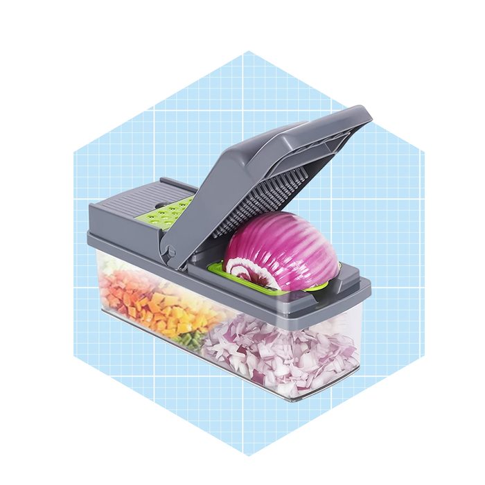 A vegetable chopper sits with a raised lid, holding a whole onion, while chopped onions and diced vegetables fill the container below.