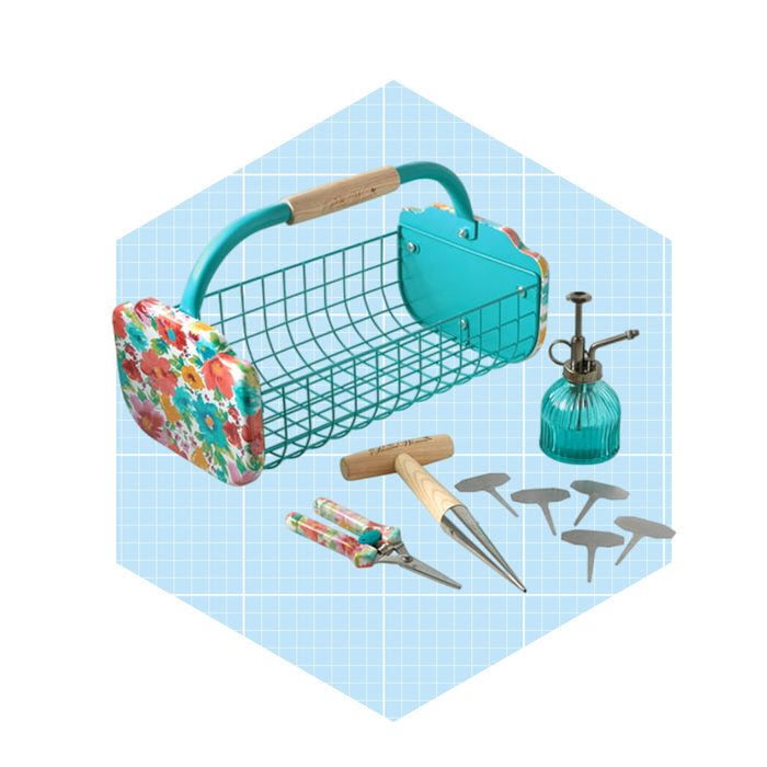 A floral-patterned basket holds gardening tools, including shears and a watering can, surrounded by metal stakes, set against a light blue grid background.