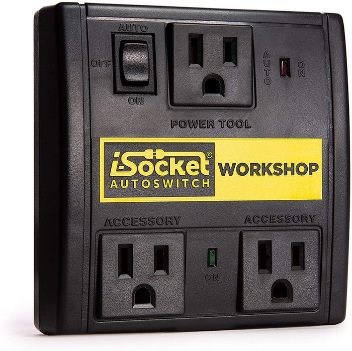 A black power switch with multiple outlets and labeled buttons is installed, designed to control power tools in a workshop environment.