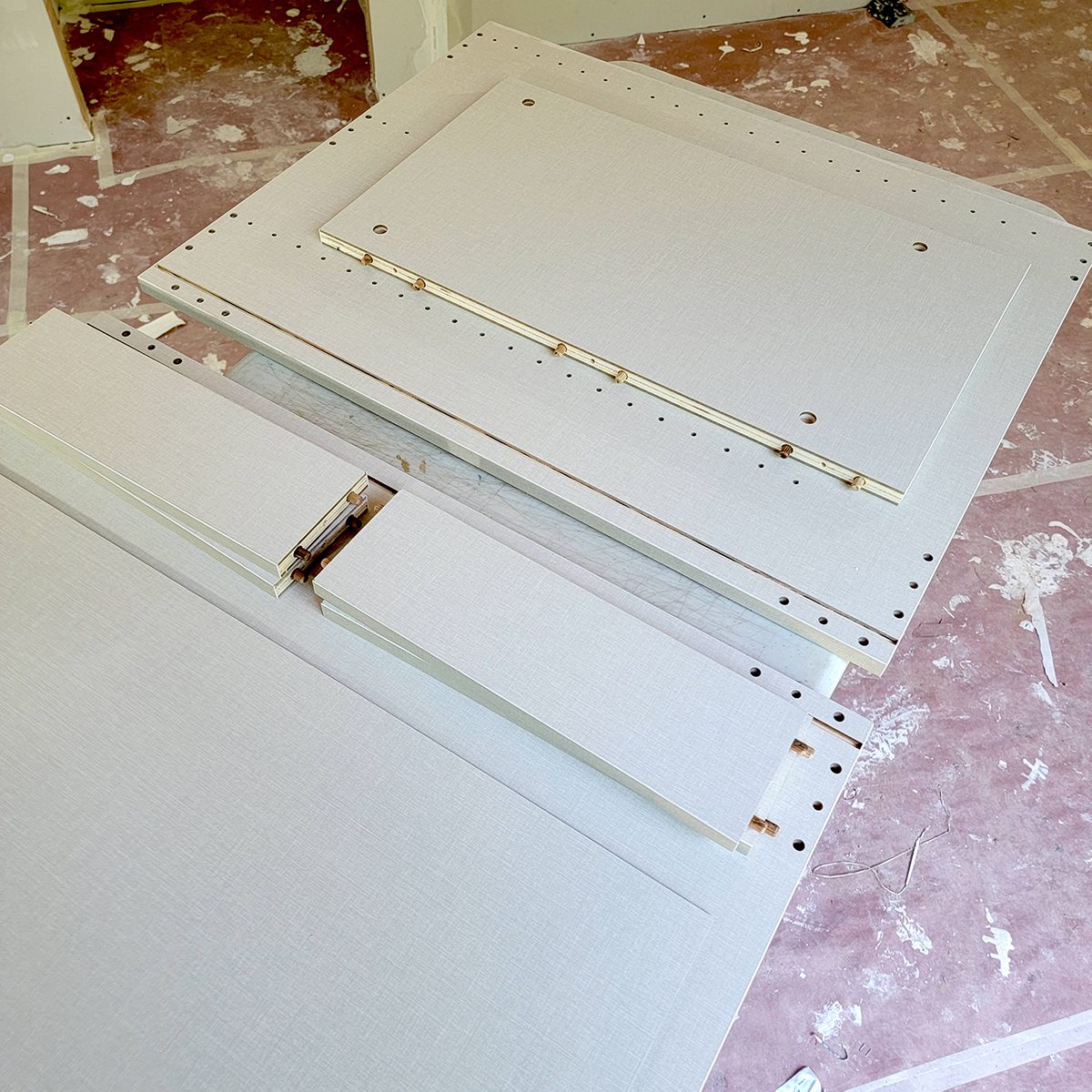 Plywood pieces are arranged on a construction surface, featuring pre-drilled holes, ready for assembly in a possibly ongoing home improvement project.