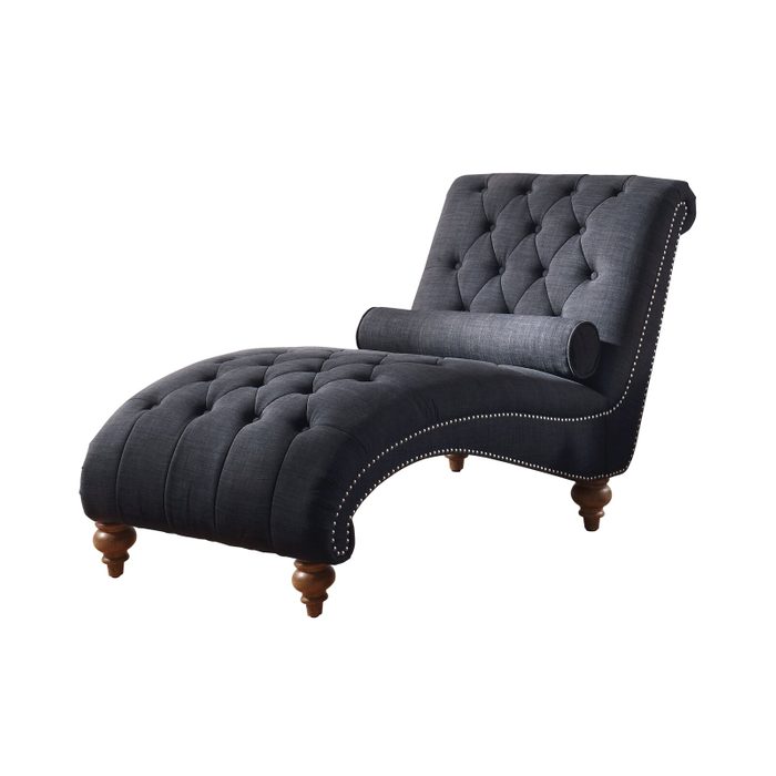 A dark upholstered chaise lounge with tufted fabric, featuring a curved design and wooden legs, rests in a minimalistic, white space.