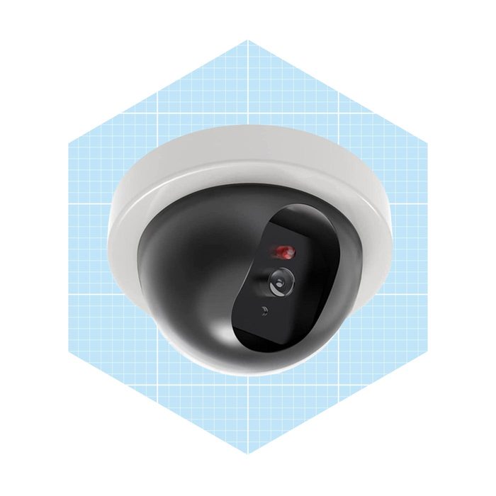 A security camera hangs from a ceiling, capturing video while surrounded by a light blue grid pattern, suggesting a modern, technological environment.