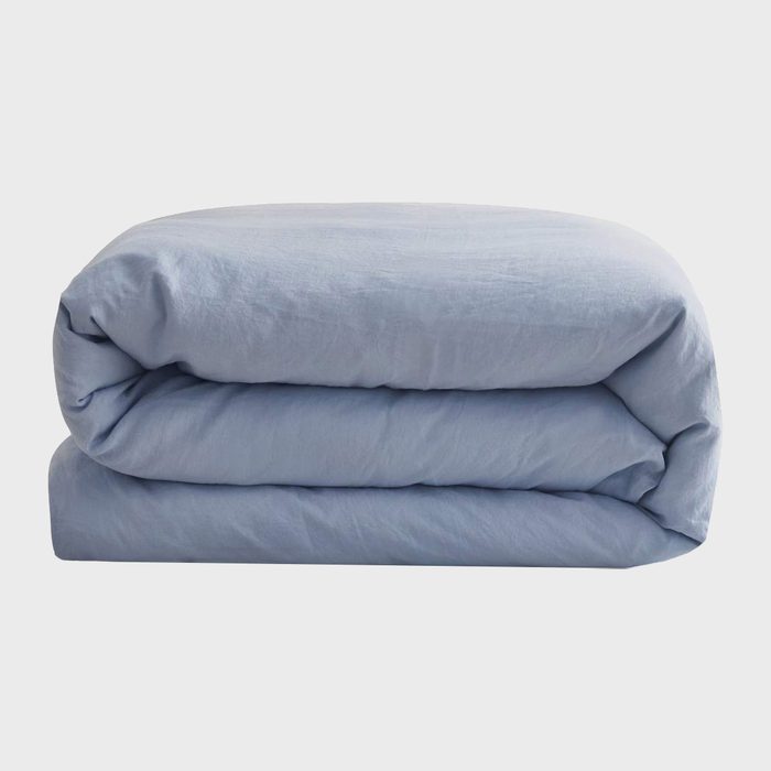 A folded light blue blanket rests on a flat surface, creating a neat and organized appearance within a minimalistic, neutral environment.