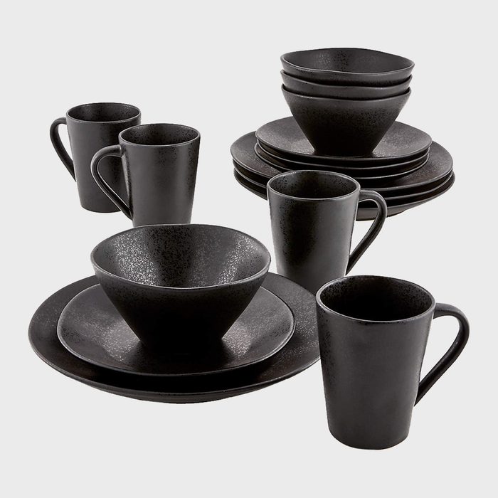 A set of black ceramic dishware including plates, bowls, and mugs is arranged neatly on a light background, showcasing a modern, minimalist design.