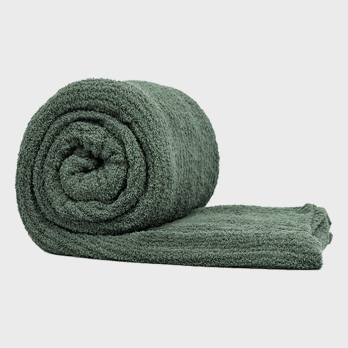 A rolled dark green towel rests flat on a light gray surface, suggesting organization and readiness for use, possibly in a bathroom or gym setting.