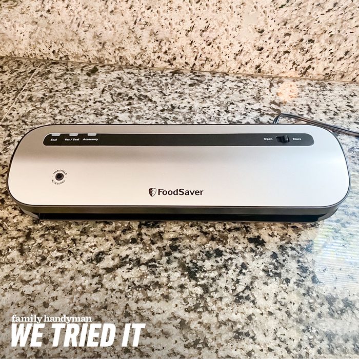 A FoodSaver vacuum sealer rests on a granite countertop, designed for preserving food by sealing bags. It features buttons for various functions.