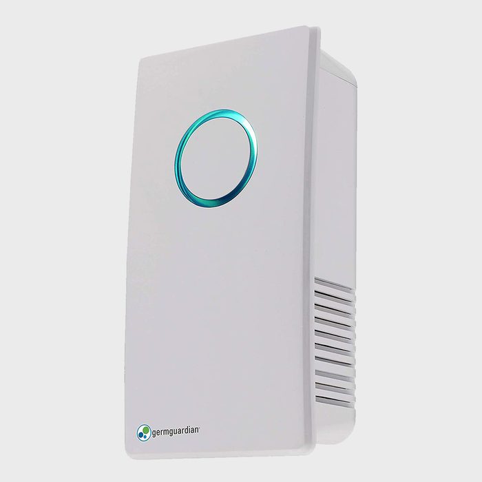 A white air purifier emits blue circular light, filtering air in a neutral-colored environment, designed to enhance indoor air quality effectively.