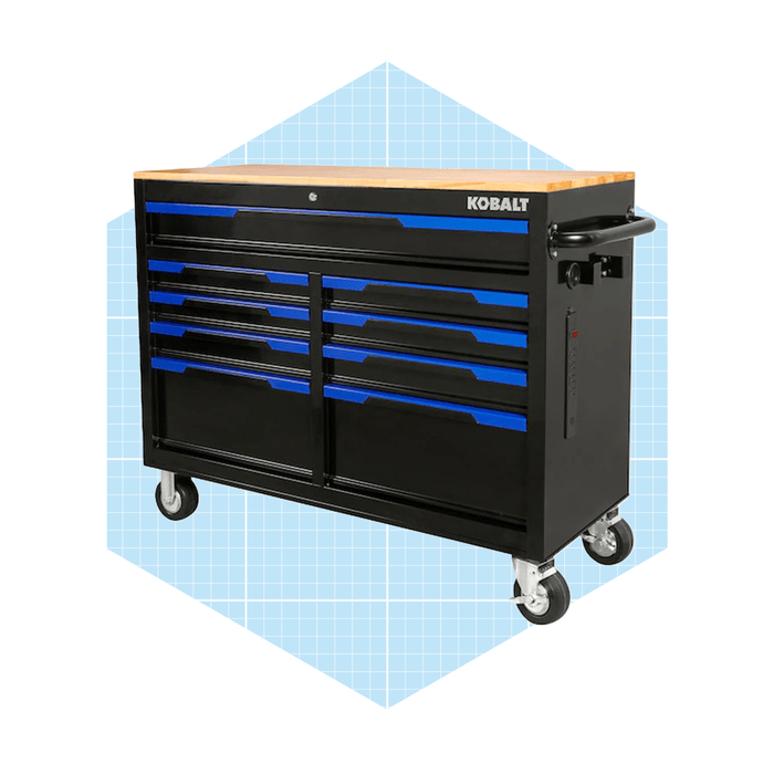 A black and blue tool chest with multiple drawers on wheels stands on a light blue grid background. It serves as an organized workspace for tools.