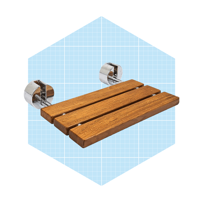 A wooden shower shelf is mounted on chrome brackets, holding toiletries in a bright, hexagonal backdrop with a light blue grid pattern.