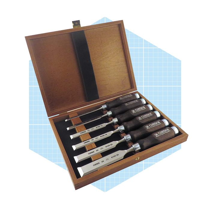 A wooden storage box displays six chisels with metal blades and dark wooden handles, resting on a black velvet base, set against a light blue background.