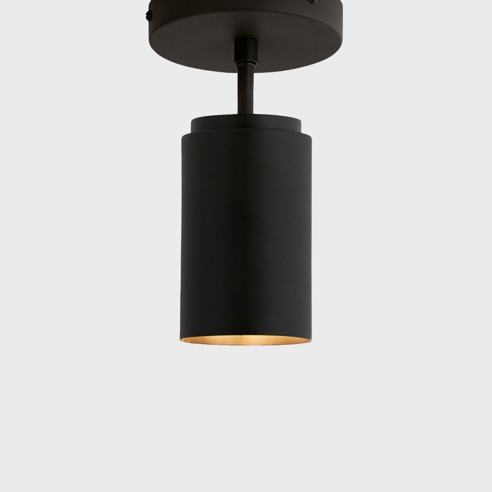 A cylindrical black pendant light illuminates from within, suspended from the ceiling against a light gray background.