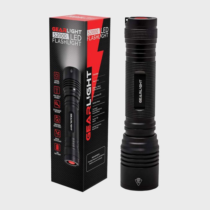 A black LED flashlight stands beside its red and black packaging, highlighting features like brightness and weather resistance. The flashlight is cylindrical with a textured grip.