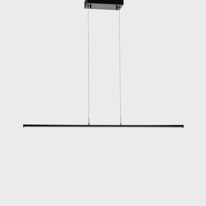 A linear black LED light fixture hangs from the ceiling by two thin wires, illuminating a minimalistic, neutral-colored space.