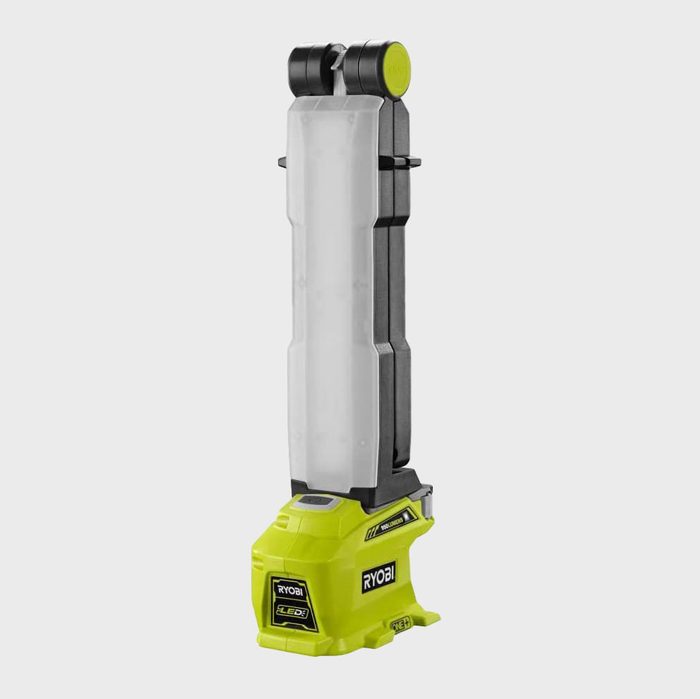A portable LED work light stands upright, illuminating its surroundings. It features a green base and a long, transparent light cover for broad illumination.