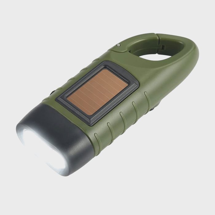 A green solar-powered flashlight emits light, designed for outdoor use, featuring a textured grip and a solar panel for recharging in natural light.