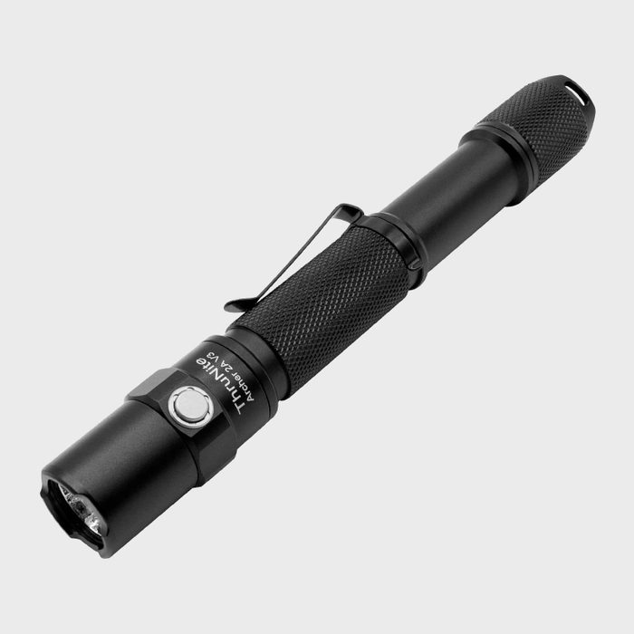 A black metal flashlight rests horizontally, featuring a textured grip and a clip. It's designed for illumination in dark environments, showcasing a sleek, portable design.