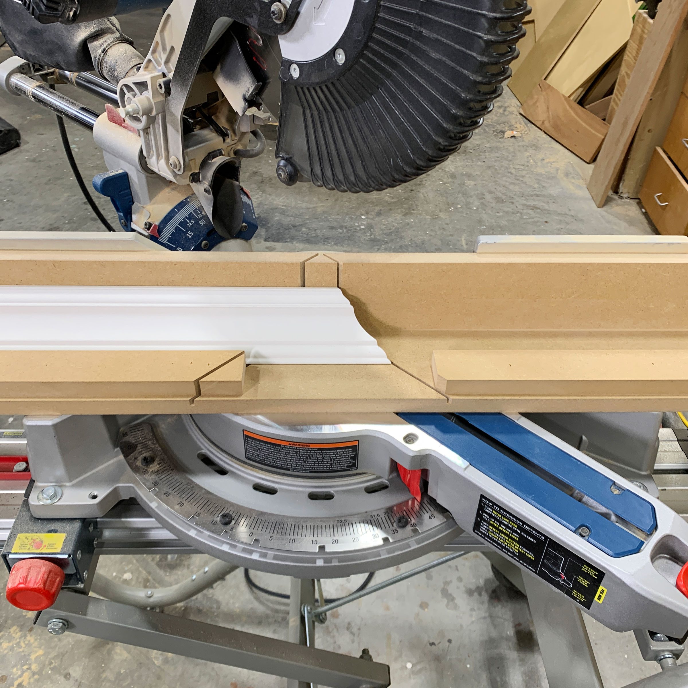 A miter saw is positioned to cut a piece of molding, showing detailed profiles and a clean workspace with tools nearby.