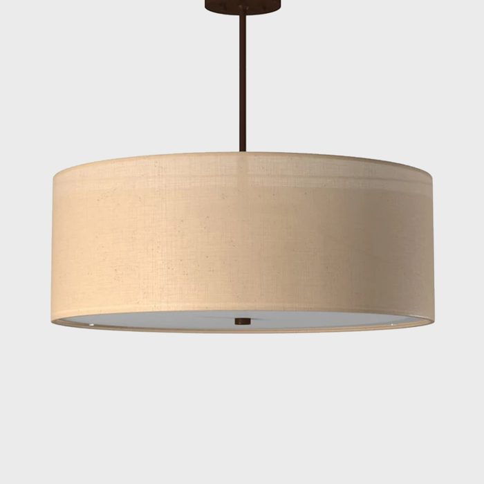 A round pendant lamp hangs from the ceiling, providing light. The beige fabric shade softens the illumination in a neutral space.