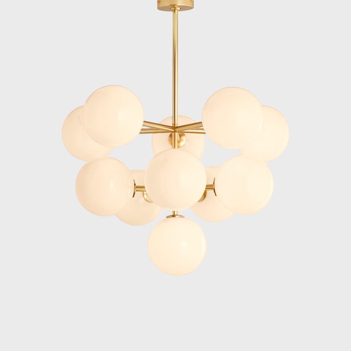 A modern chandelier features multiple round, white glass bulbs arranged symmetrically around a central gold fixture, hanging against a plain background.