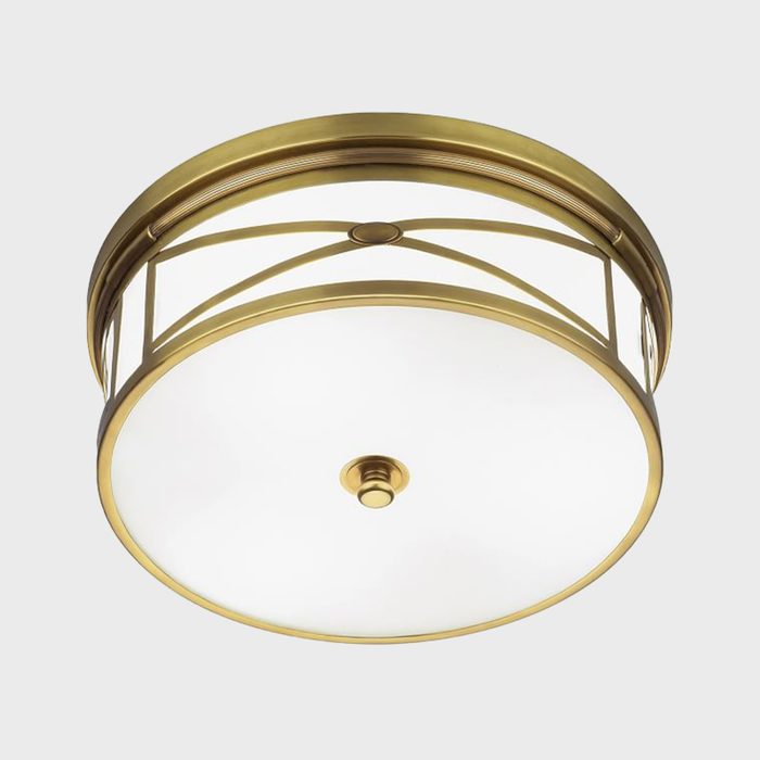 A round ceiling light features a frosted glass shade surrounded by a decorative brass frame, illuminating interior spaces with a warm glow.