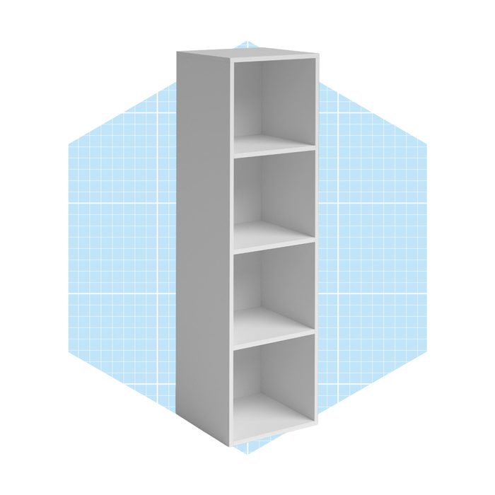 A white bookshelf stands upright, showcasing four empty shelves, against a light blue grid-patterned background. The setting emphasizes its minimalist design.