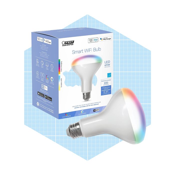 A smart LED bulb glows with a rainbow gradient, sitting beside its packaging on a light blue geometric background, indicating features like WiFi connectivity and voice control.
