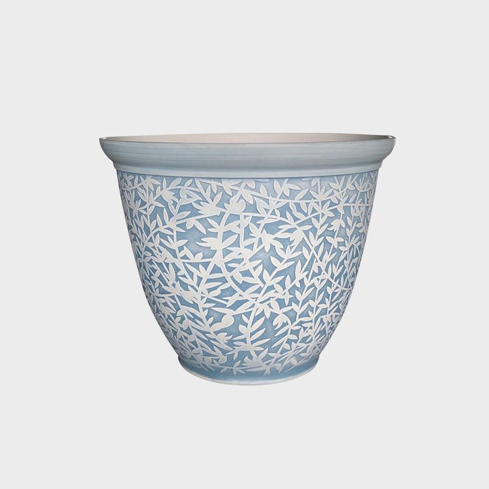 A decorative blue pot features intricate white leaf patterns, positioned upright against a plain background, designed for holding plants.
