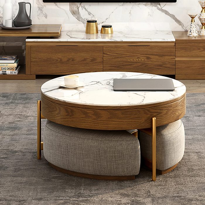A round coffee table with a marble top displays a laptop and a cup, surrounded by a cozy living space with wooden furnishings and a plush rug.