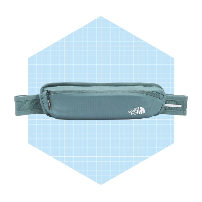 A teal waist bag lies flat, featuring a zipper and adjustable strap, against a light blue grid background, suggesting a casual outdoor accessory.