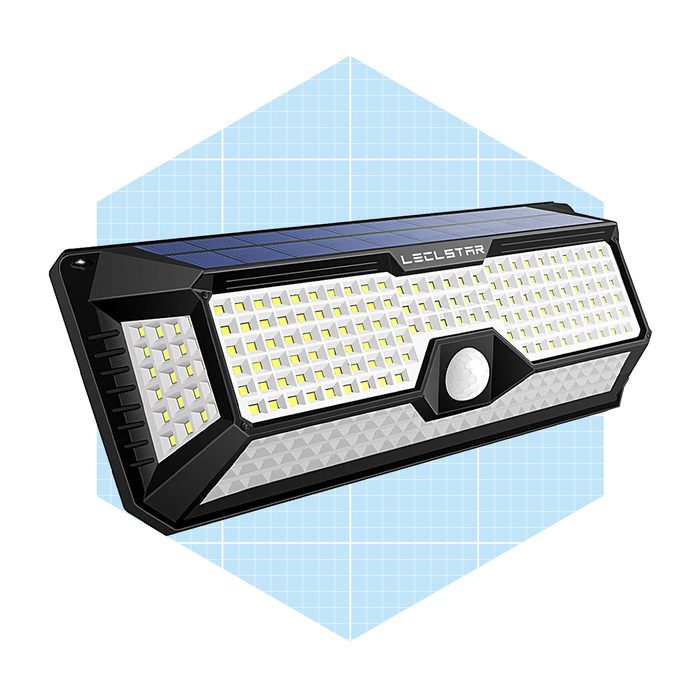 A solar-powered motion sensor light illuminates an area by activating upon detecting movement, set against a light blue geometric background.