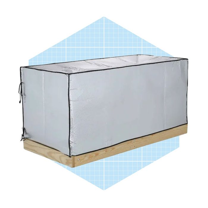 A rectangular box with a silver, insulated exterior rests on a wooden base, surrounded by a light blue geometric background.
