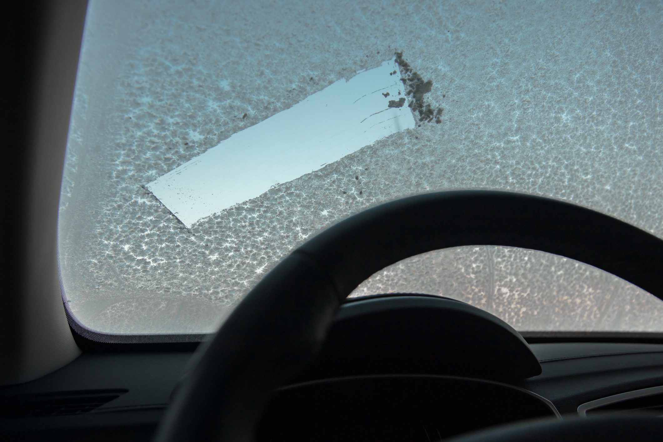 Frosty morning and Ice covered window car. removing the snow from the window of the car