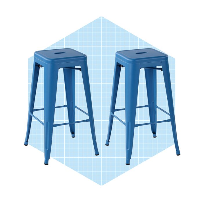 Two blue metal stools stand upright against a light blue geometric background, showcasing their simple, modern design suitable for casual seating.