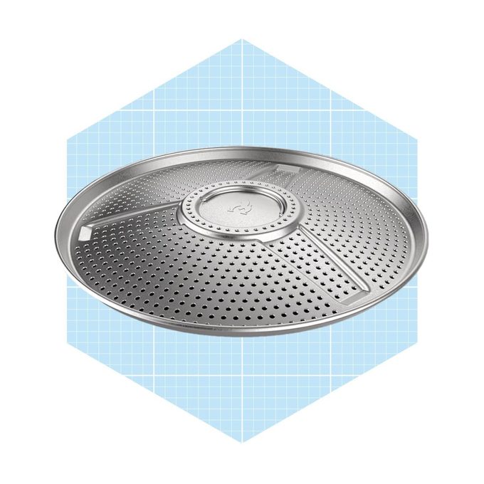 A metal baking tray with perforations sits centrally on a light blue grid-patterned background, designed for even heat distribution during cooking.