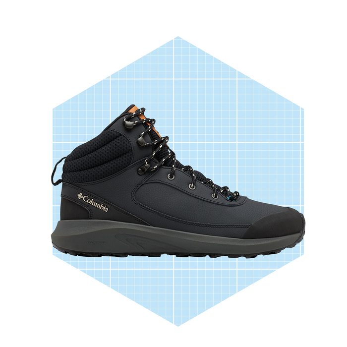 A black hiking boot stands upright, with laces threaded through metal hooks. It's set against a light blue grid background, indicating a promotional or design context.